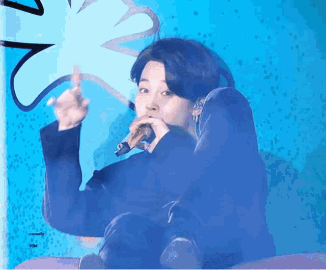 a man is singing into a microphone in front of a blue wall .