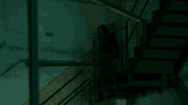 a woman is walking up a set of stairs with a sign on the wall that says exit