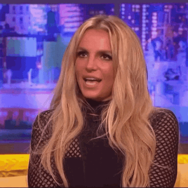 britney spears is sitting on a couch talking on a show .