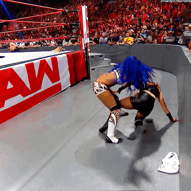 two women wrestling in front of a sign that says raw on it