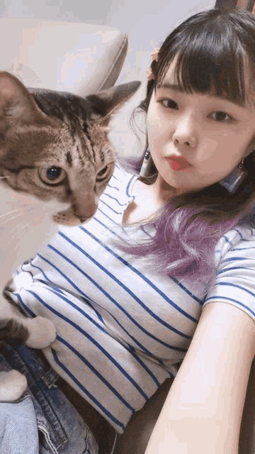 a woman in a striped shirt holds a cat in her lap
