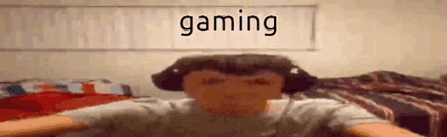 a man wearing headphones is sitting in front of a wall with the word gaming on it .