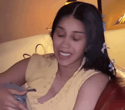 a woman in a yellow tank top is sitting on a couch