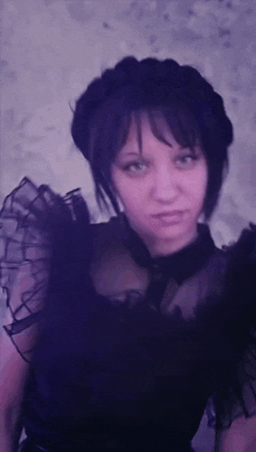 a woman wearing a black dress with ruffled sleeves