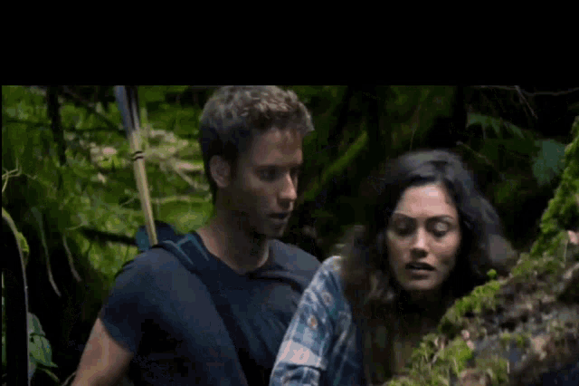 a man and a woman are standing next to each other in a jungle