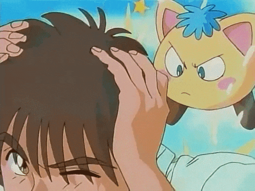 a person touching another person 's head with a yellow cat behind them