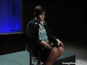 a man is sitting in a chair with his legs crossed in front of a freegifmaker.me sign
