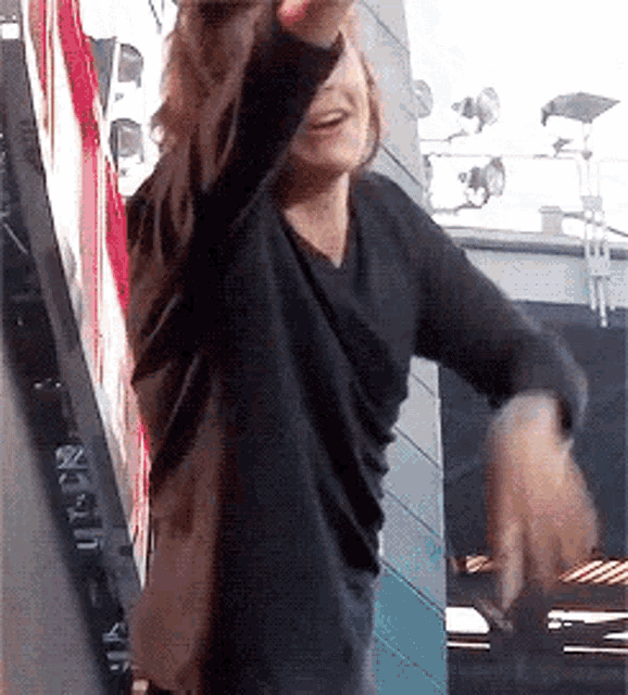a woman in a black sweater is dancing in front of a sign that says ' netflix ' on it
