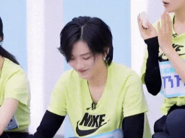 a woman wearing a yellow nike t-shirt is sitting next to a man .