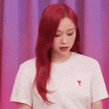 a woman with red hair is wearing a white t-shirt with a heart embroidered on it .