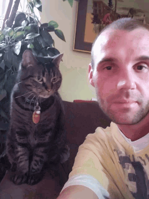 a man taking a selfie with a cat that has a tag that says ' a ' on it