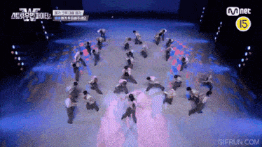 a group of people are dancing on a stage with a mnet logo in the background