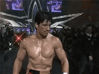 a shirtless boxer is standing in front of a crowd of people