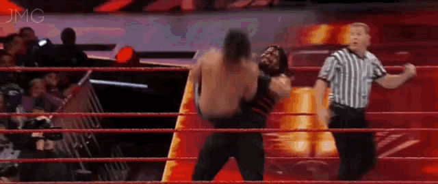 a wrestler is being lifted in the air by another wrestler while a referee watches .