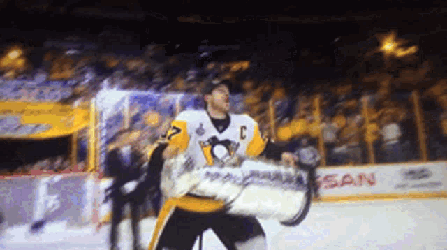 a hockey player is holding a trophy in front of a nissan sign