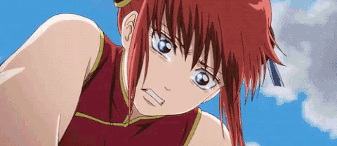 a girl with red hair and blue eyes is wearing a red top and looking at the camera .
