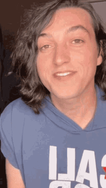 a young man with long hair is wearing a blue shirt that says ljas on it