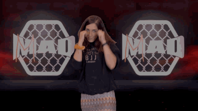 a woman stands in front of a logo that says mad