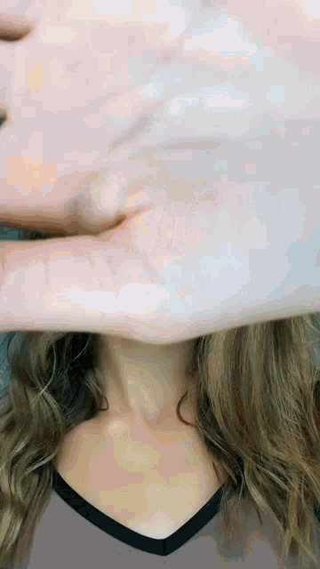 a woman covering her face with her hand while wearing a pink shirt