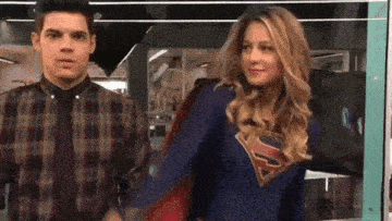 a man and a woman are standing next to each other and the woman is wearing a superman costume