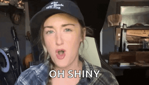 a woman wearing a new york hat is making a funny face and saying oh shiny