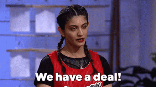 a woman in a red basketball jersey is standing in front of a blue wall and says `` we have a deal '' .