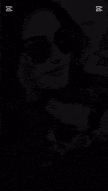 a woman wearing sunglasses is kissing a man on the neck .