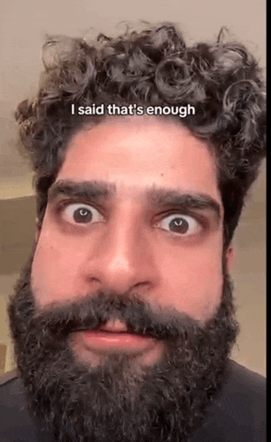 a man with a beard and curly hair is making a face .