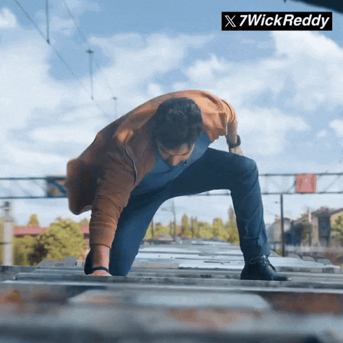 a man is crawling on a railroad track with a 7wick reddy logo in the background