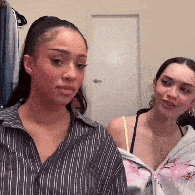 two young women are standing next to each other in a room .