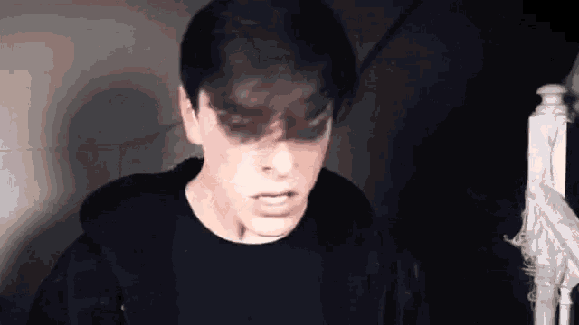 a young man in a black shirt is standing in a dark room .