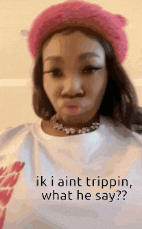 a woman wearing a pink hat and a white shirt with the words `` ik i aint trippin , what he say '' .