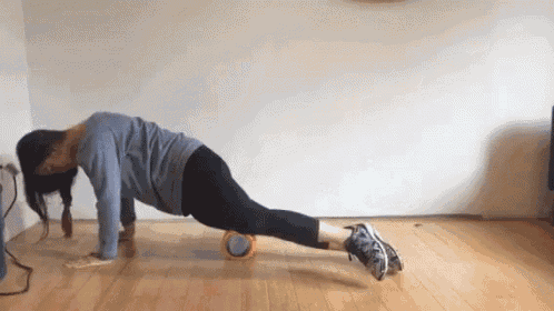a woman is doing push ups on a foam roller in a living room .