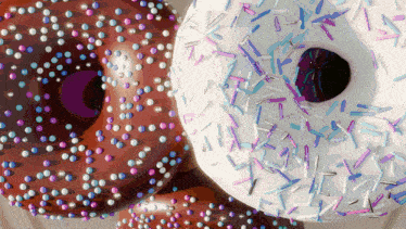 a chocolate donut and a white donut with purple and blue sprinkles