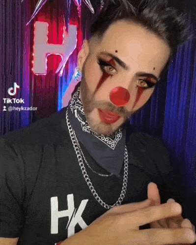 a man dressed as a clown with a red nose and a black shirt that says hk