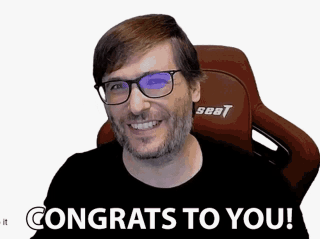 a man with glasses and a beard is smiling and saying congrats to you !
