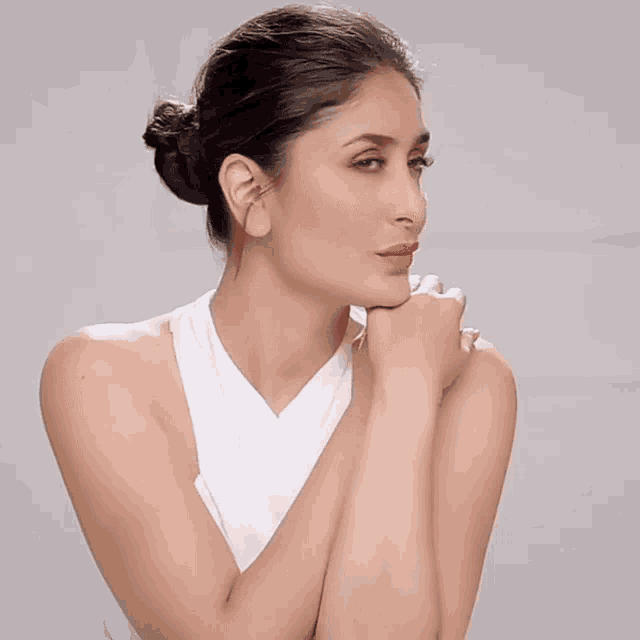 a woman in a white tank top has her hands on her face