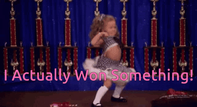 a little girl is dancing in front of trophies and the words actually won something