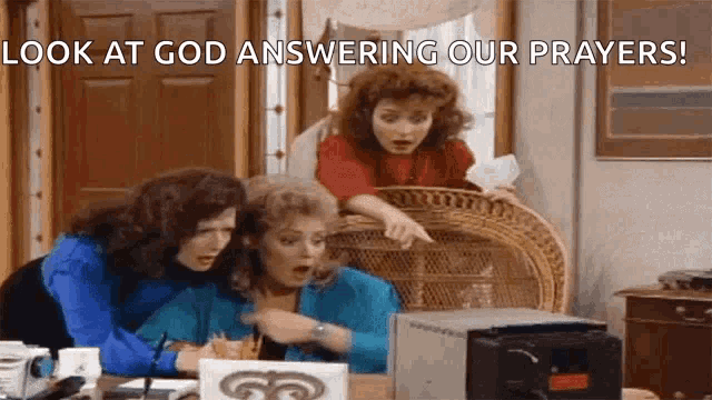 three women are sitting at a table with a sign that says look at god answering our prayers .