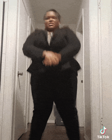 a woman in a suit is dancing in a hallway with tiktok written on the bottom left