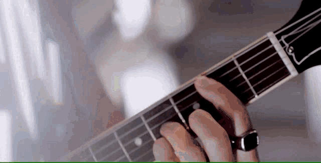 a person is playing an acoustic guitar with a ring on their finger