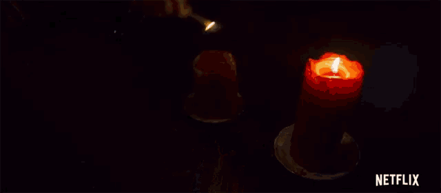 two lit candles are on a table with a netflix logo in the corner