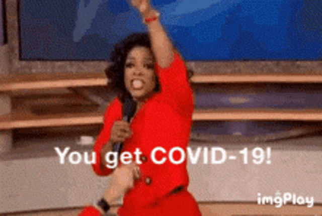 a woman in a red dress is holding a microphone and says " you get covid-19 ! "