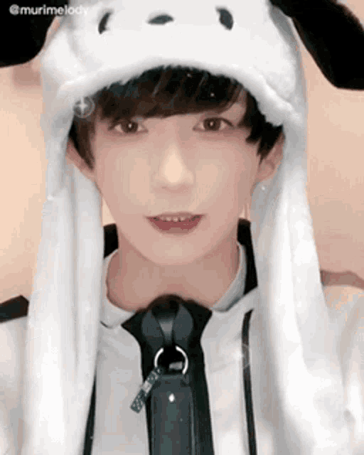 a young boy wearing a white hat with ears and a tie .