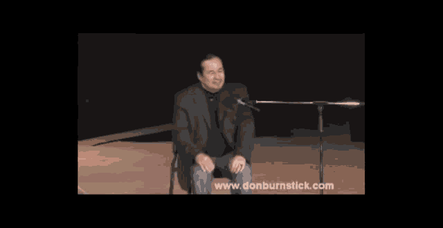 a man sitting in front of a microphone with the website www.donburnstick.com on the bottom right