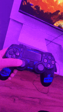 a video game controller sits on a wooden table in front of a tv