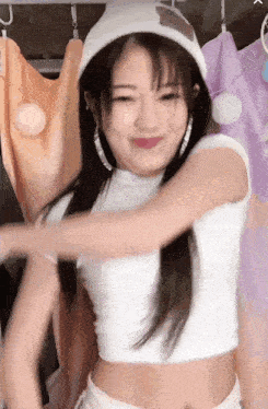 a woman wearing a white hat and a white crop top is dancing in a room .