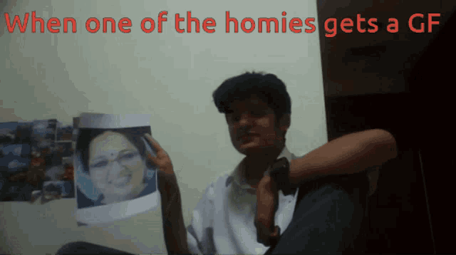 a man holding a picture of a woman with the words when one of the homies gets a gf below him