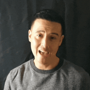 a man in a gray shirt is making a funny face