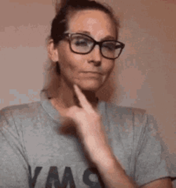a woman wearing glasses and a t-shirt is making a funny face .